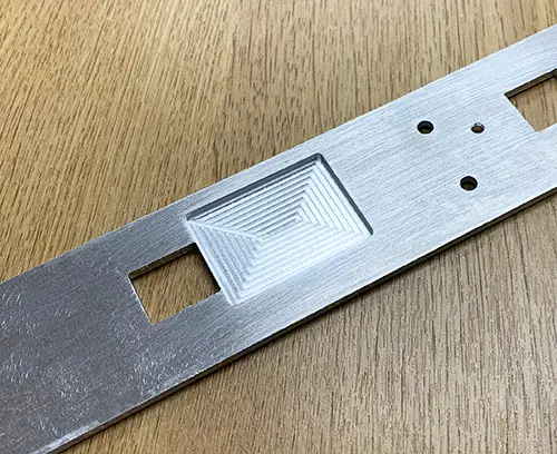 Encoche usinée dans la face arrière d'un panneau avant pour la localisation d'un composant électronique.